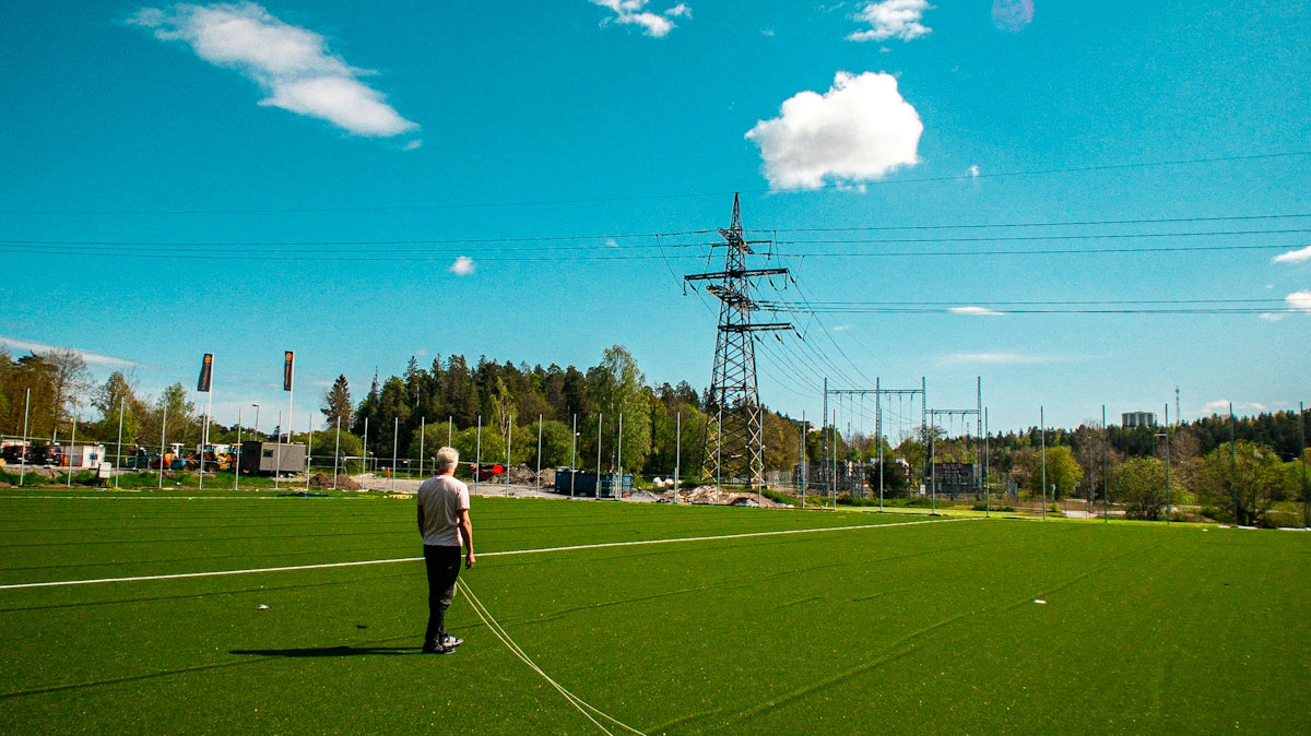 man in white shirt and black pants standing on green grass field during daytime