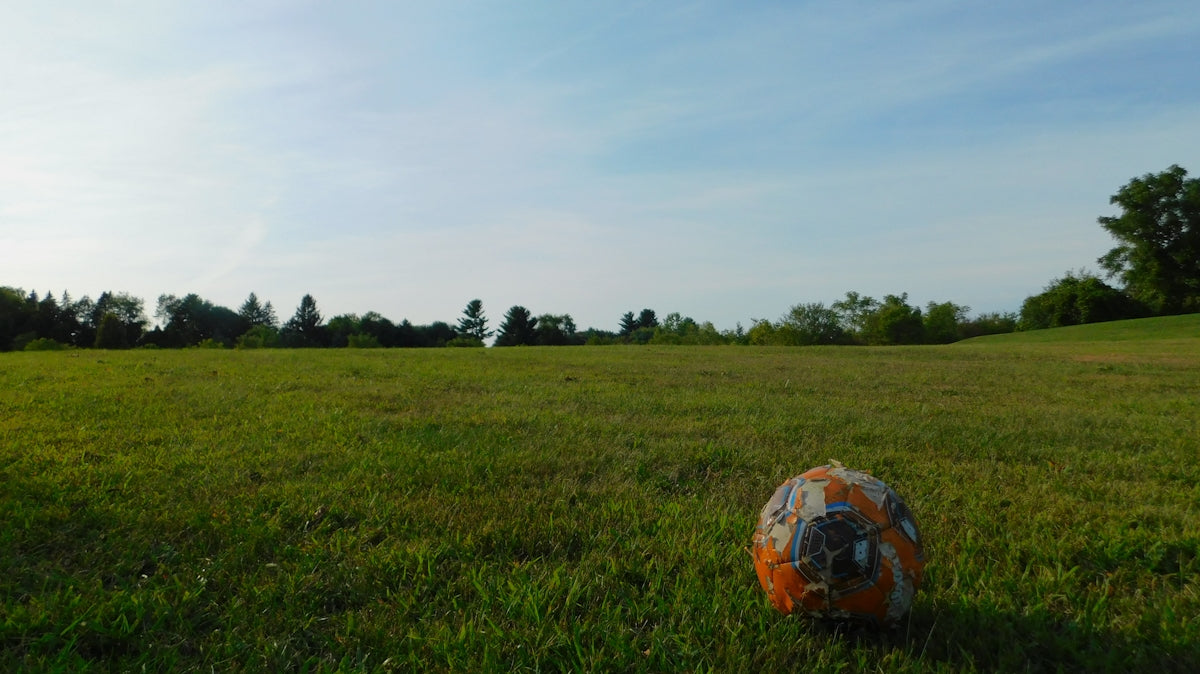 red soccer ball on green grass field under white clouds during daytime