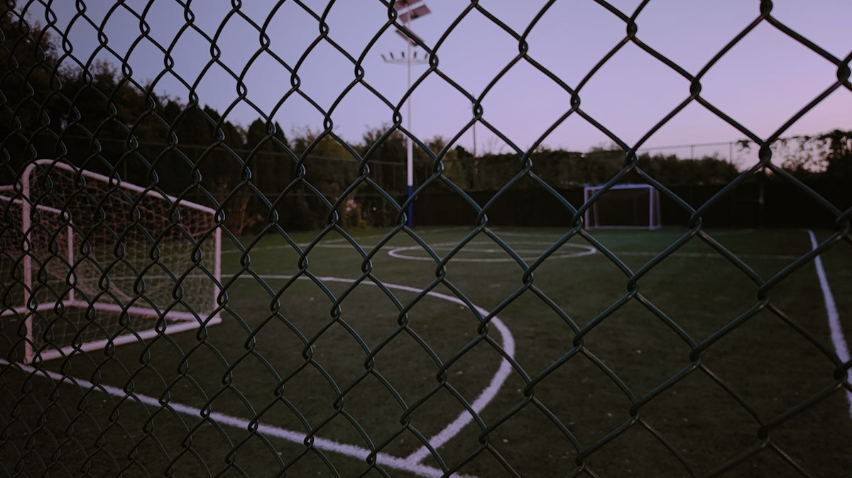 a basketball hoop is seen through a chain link fence