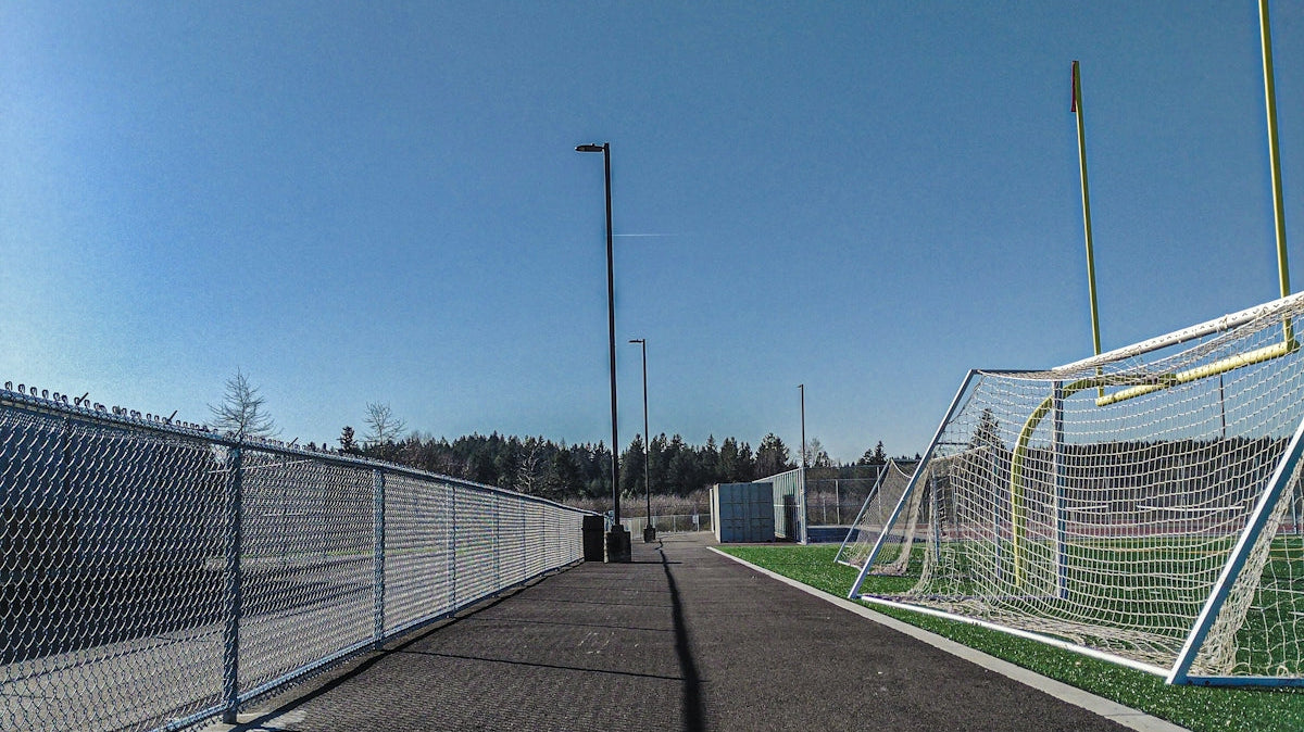a fenced in soccer field with a soccer goal