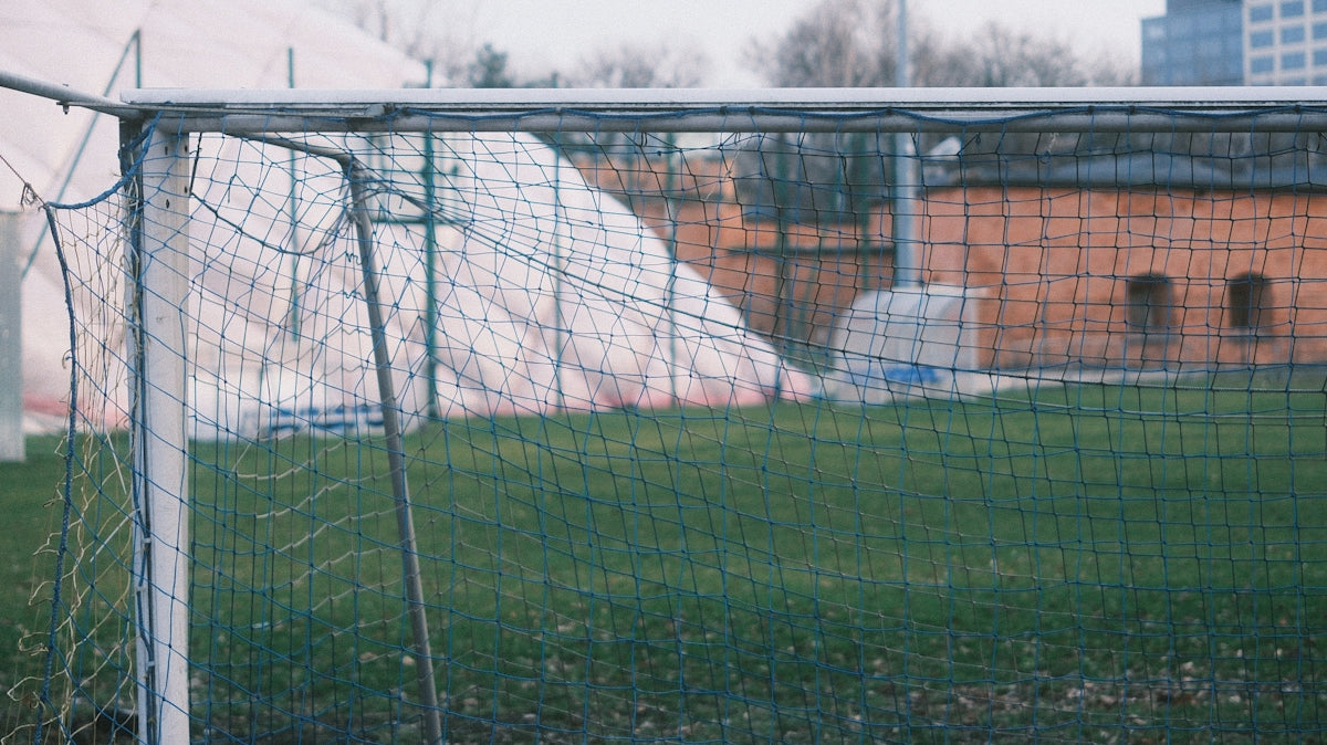 a soccer goal in a field with a building in the background