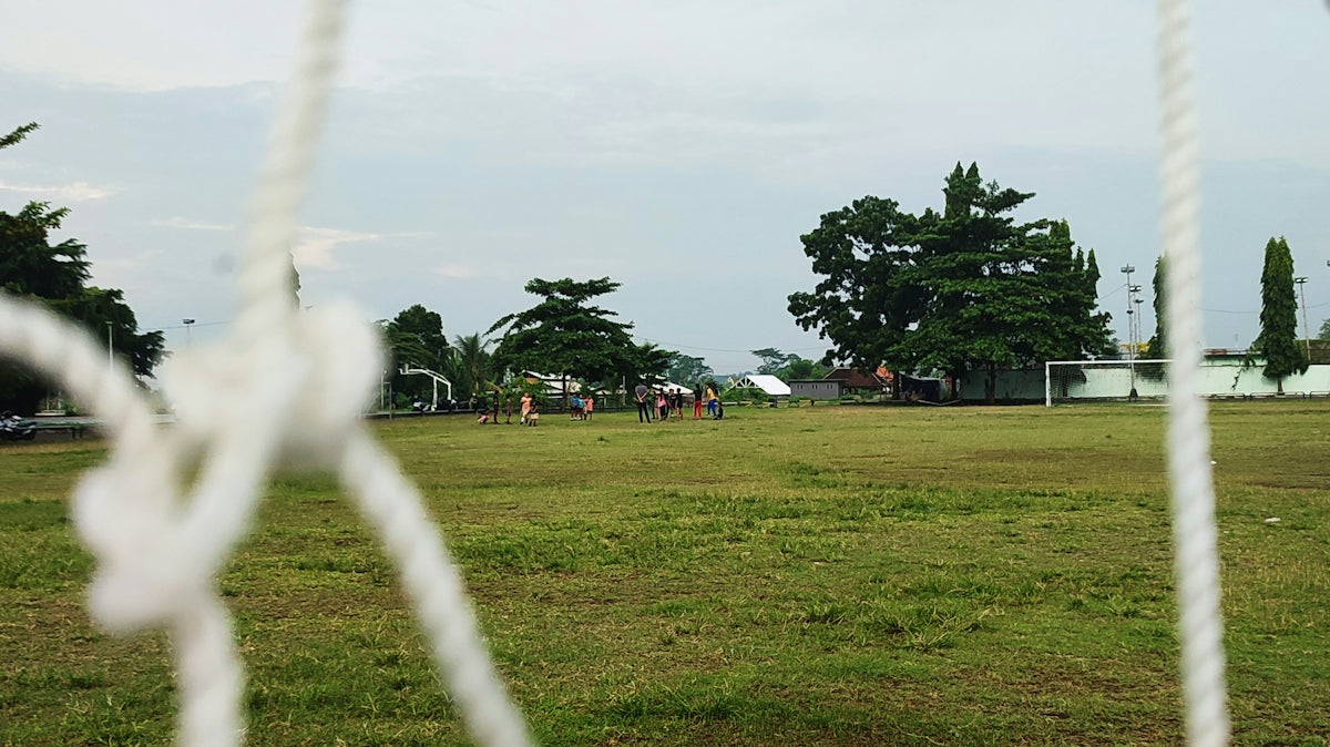 A close up of a soccer goal net with trees in the background