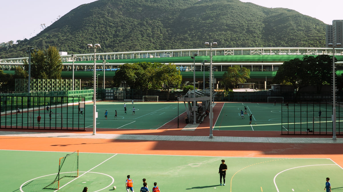 Children play soccer on a field with mountains.