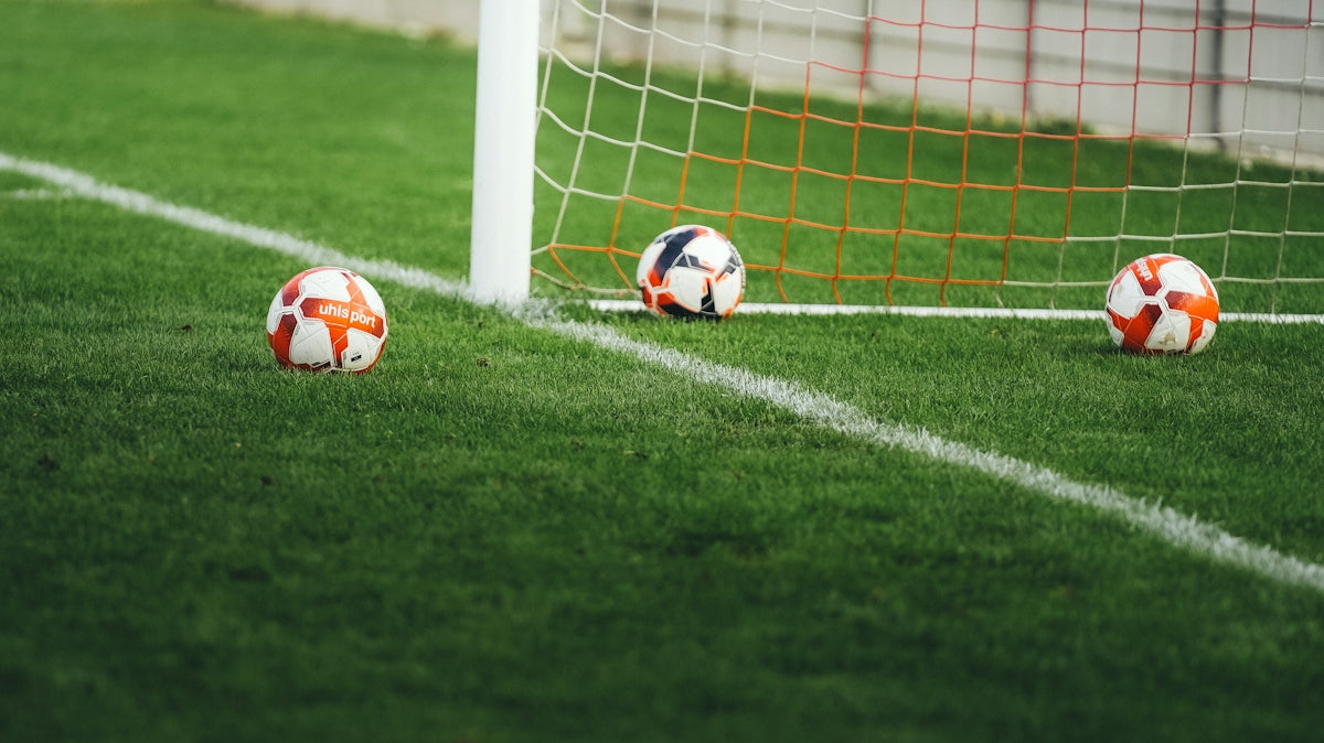Three soccer balls near a goal net