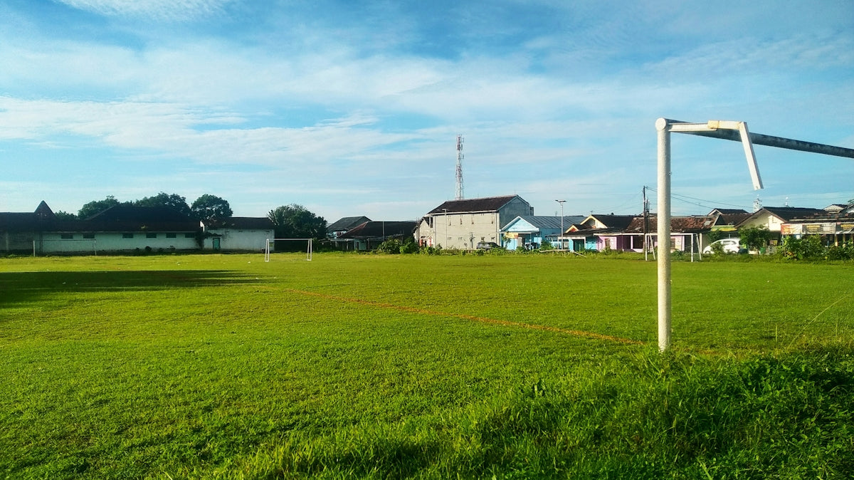 Green soccer field with goalposts under blue sky