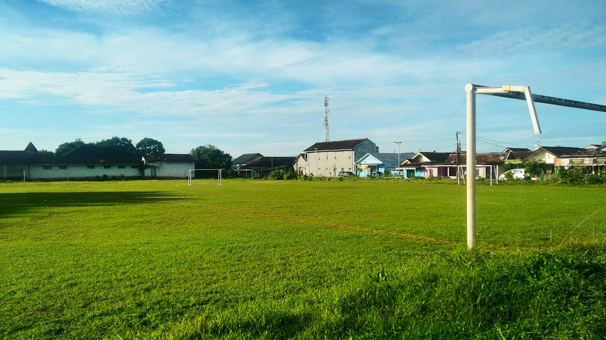 Green soccer field with goalposts under blue sky