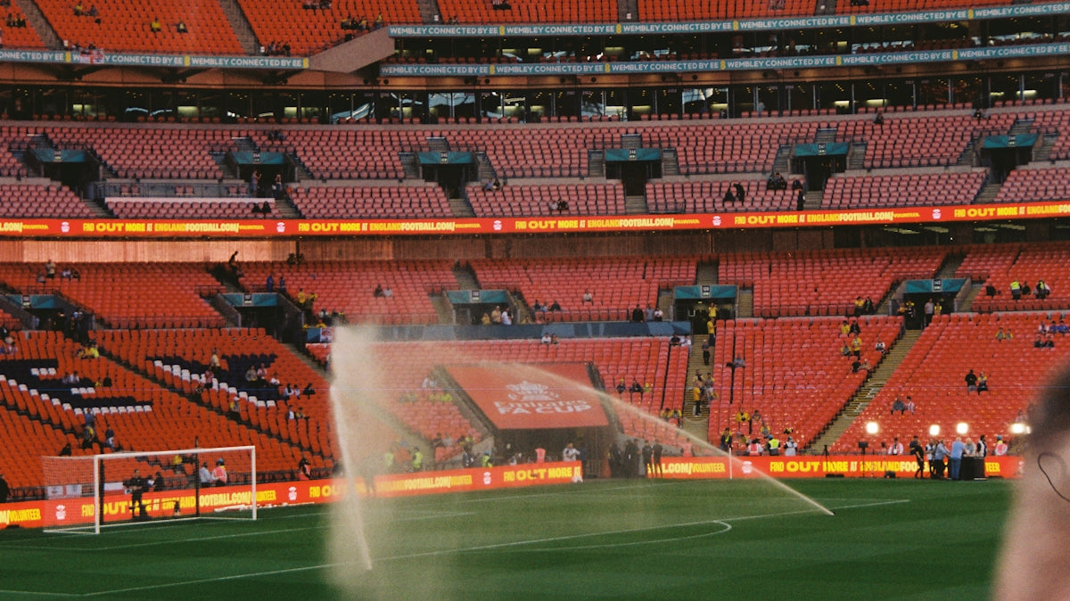 Sprinklers watering a soccer field in a stadium.