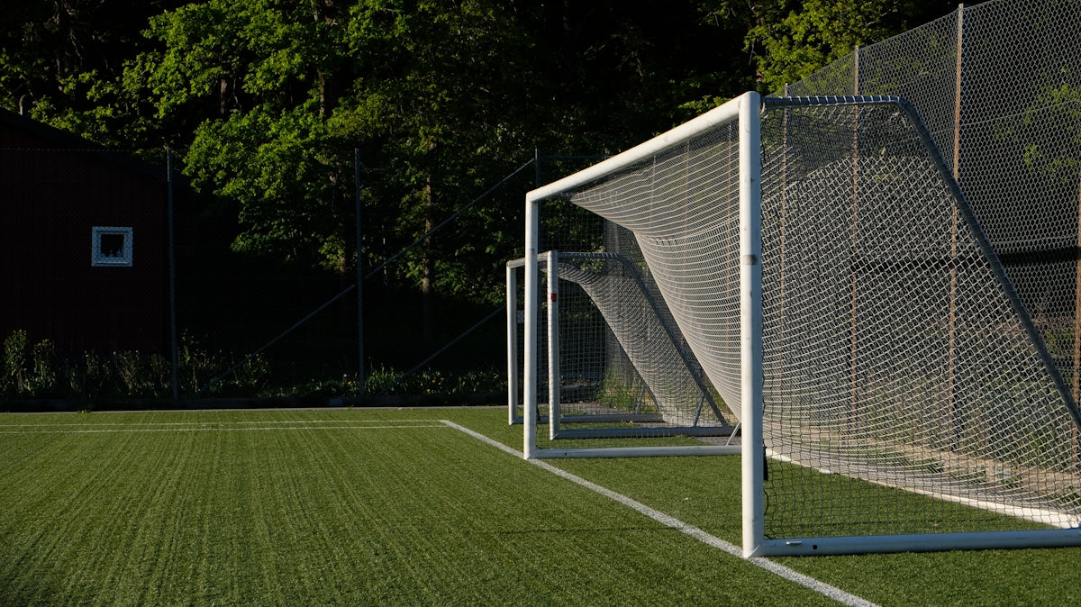 A white soccer goal on a green artificial turf field.