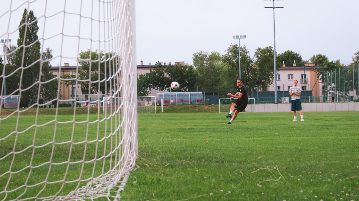 Soccer player kicking ball towards goal on green field