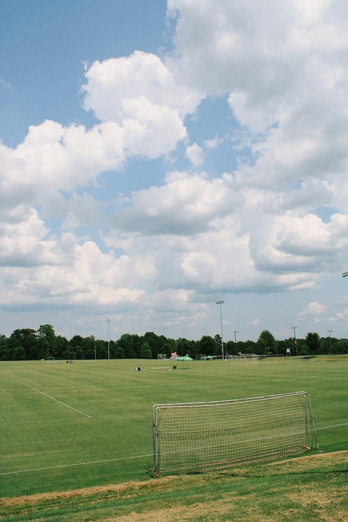 white metal fence on green grass field under white clouds during daytime