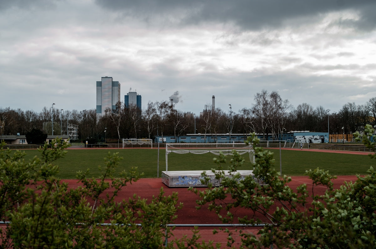 green grass field near city buildings under white clouds during daytime