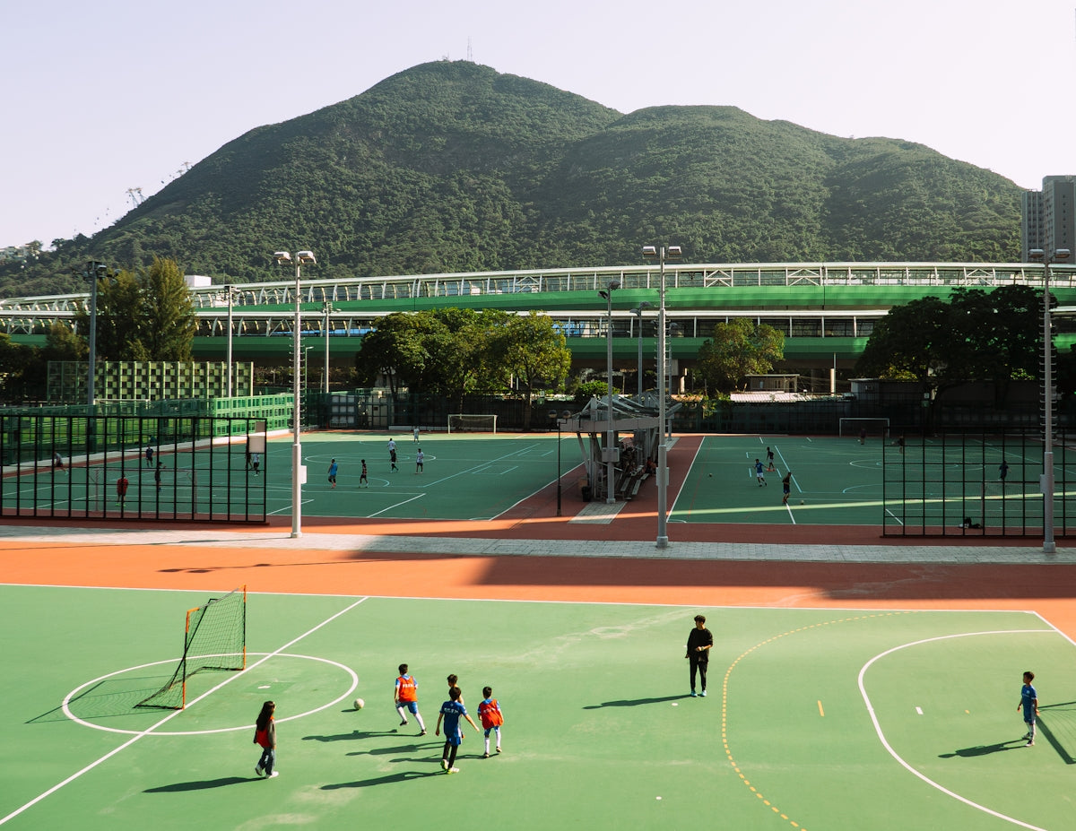 Children play soccer on a field with mountains.