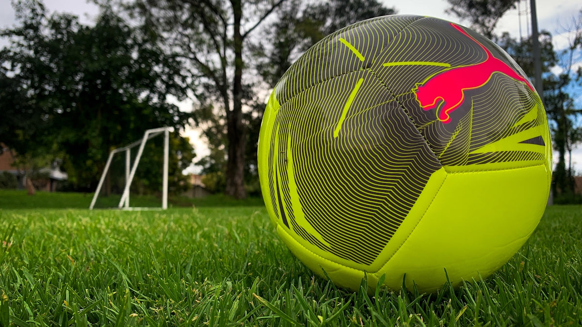 A neon yellow soccer ball on green grass.