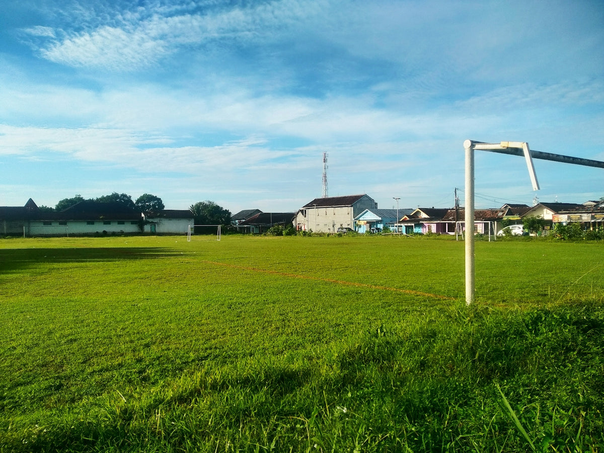 Green soccer field with goalposts under blue sky