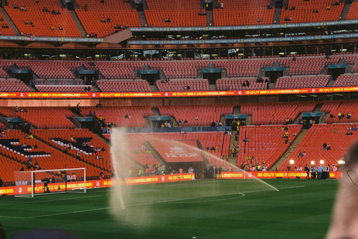 Sprinklers watering a soccer field in a stadium.