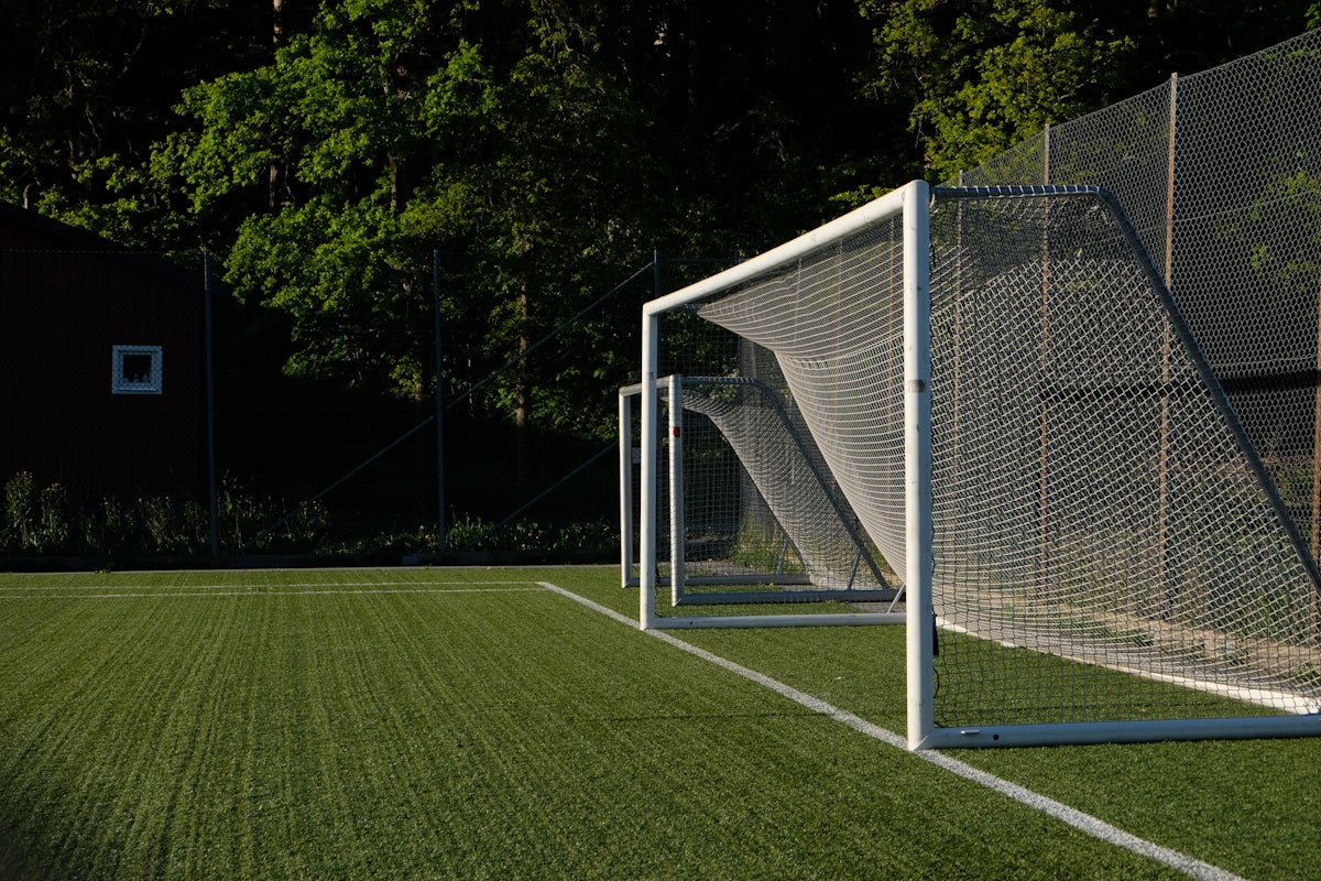 A white soccer goal on a green artificial turf field.
