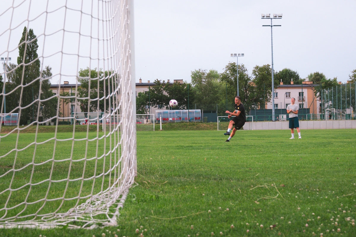 Soccer player kicking ball towards goal on green field